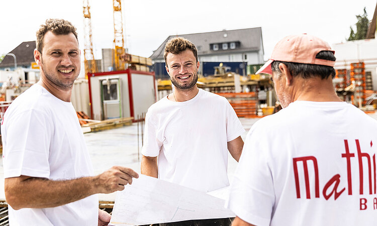 Marco Mathis und zwei Mitarbeiter von Mathis Bau auf einer Baustelle