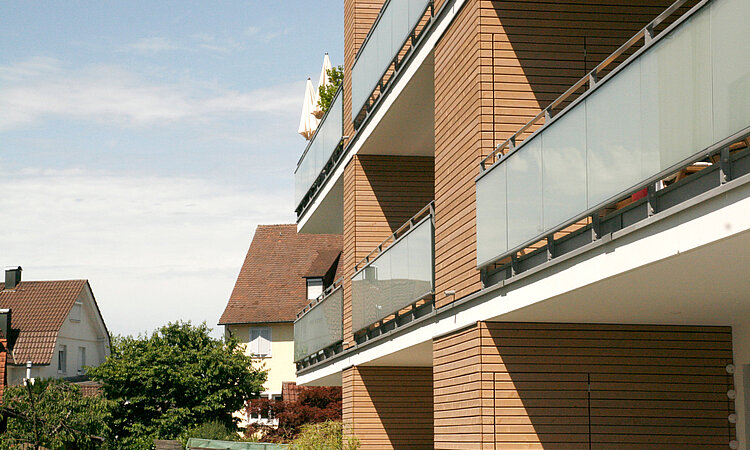 Ein Wohnhaus mit Balkons und Bäumen im Hintergrund